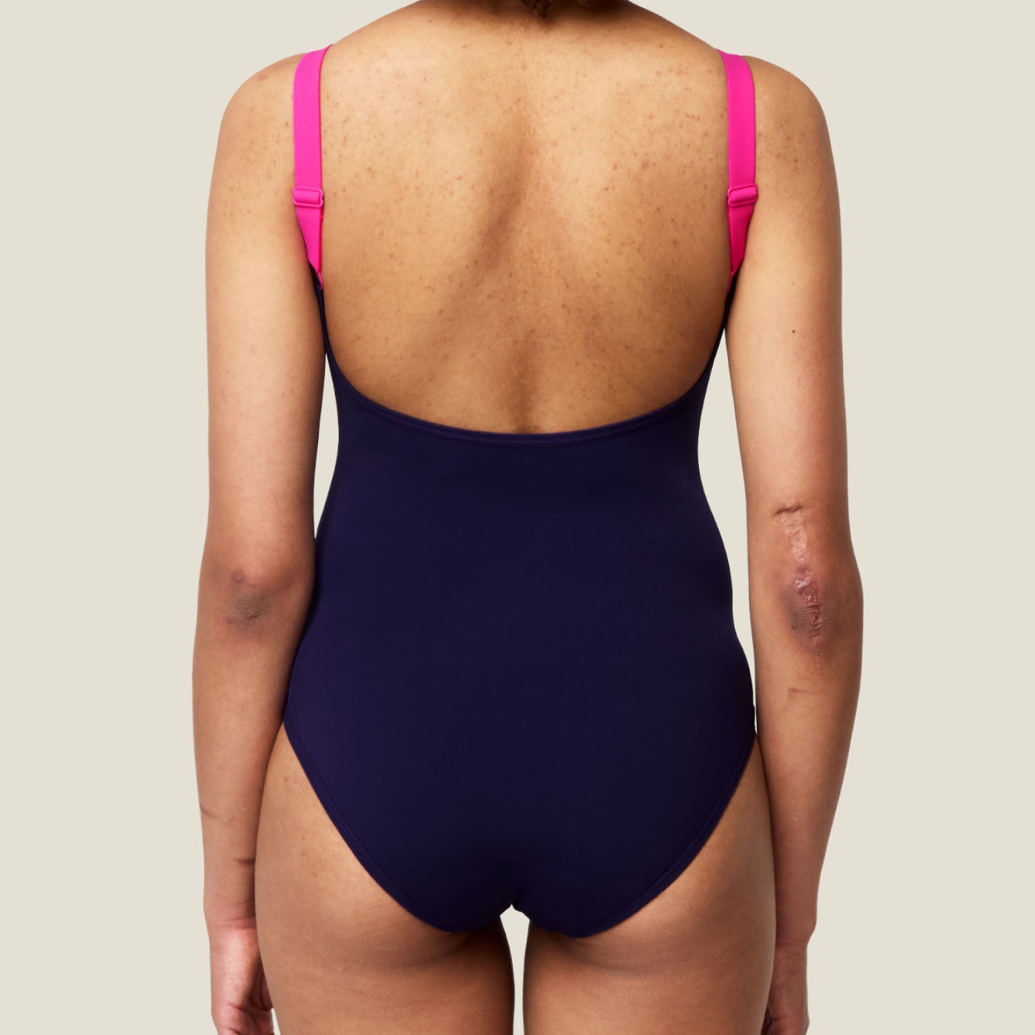 Back view of the WUKA Period Scoopback Swimsuit in pink and purple, highlighting leak-proof coverage and comfortable scoop design.