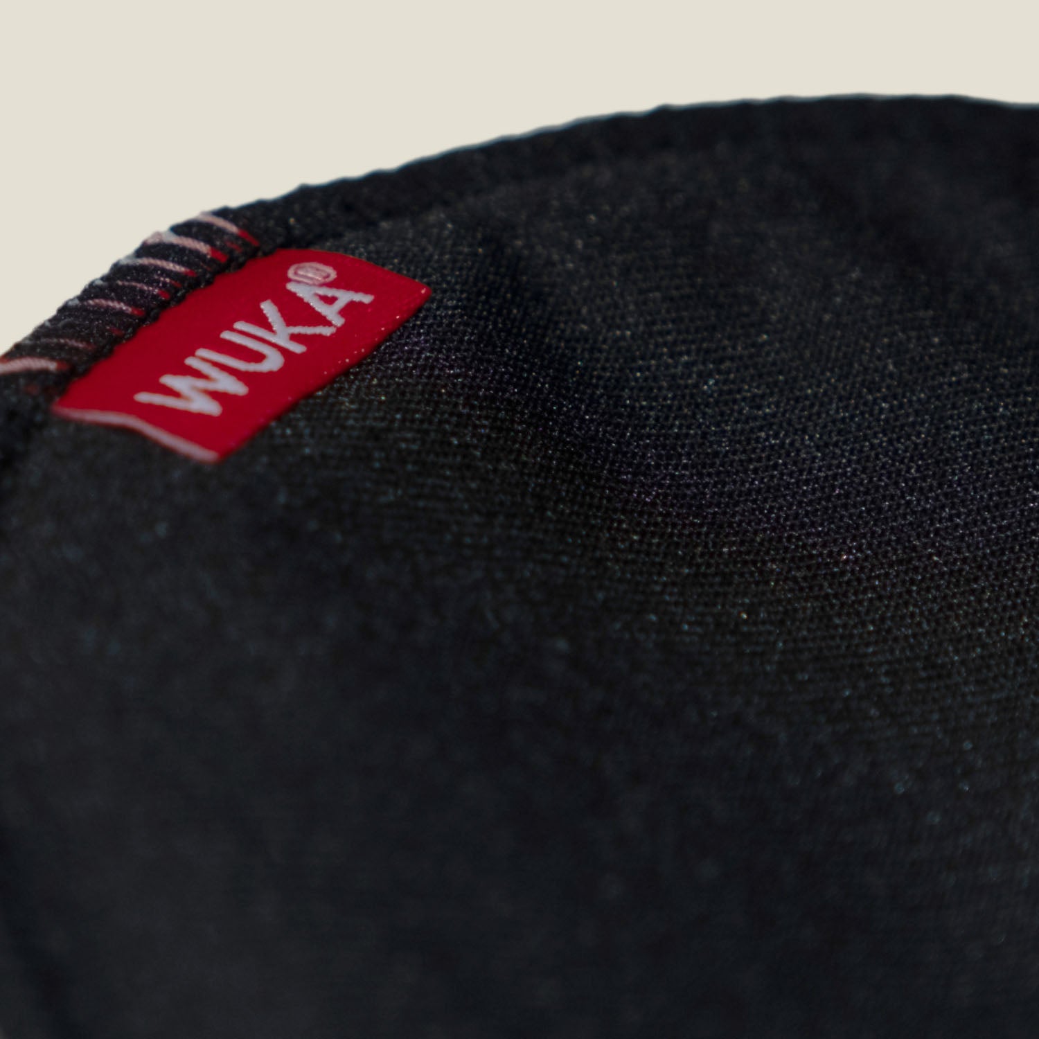 Detailed view of the WUKA logo tag stitched on the premium black nursing pad fabric, emphasizing brand identity and quality.