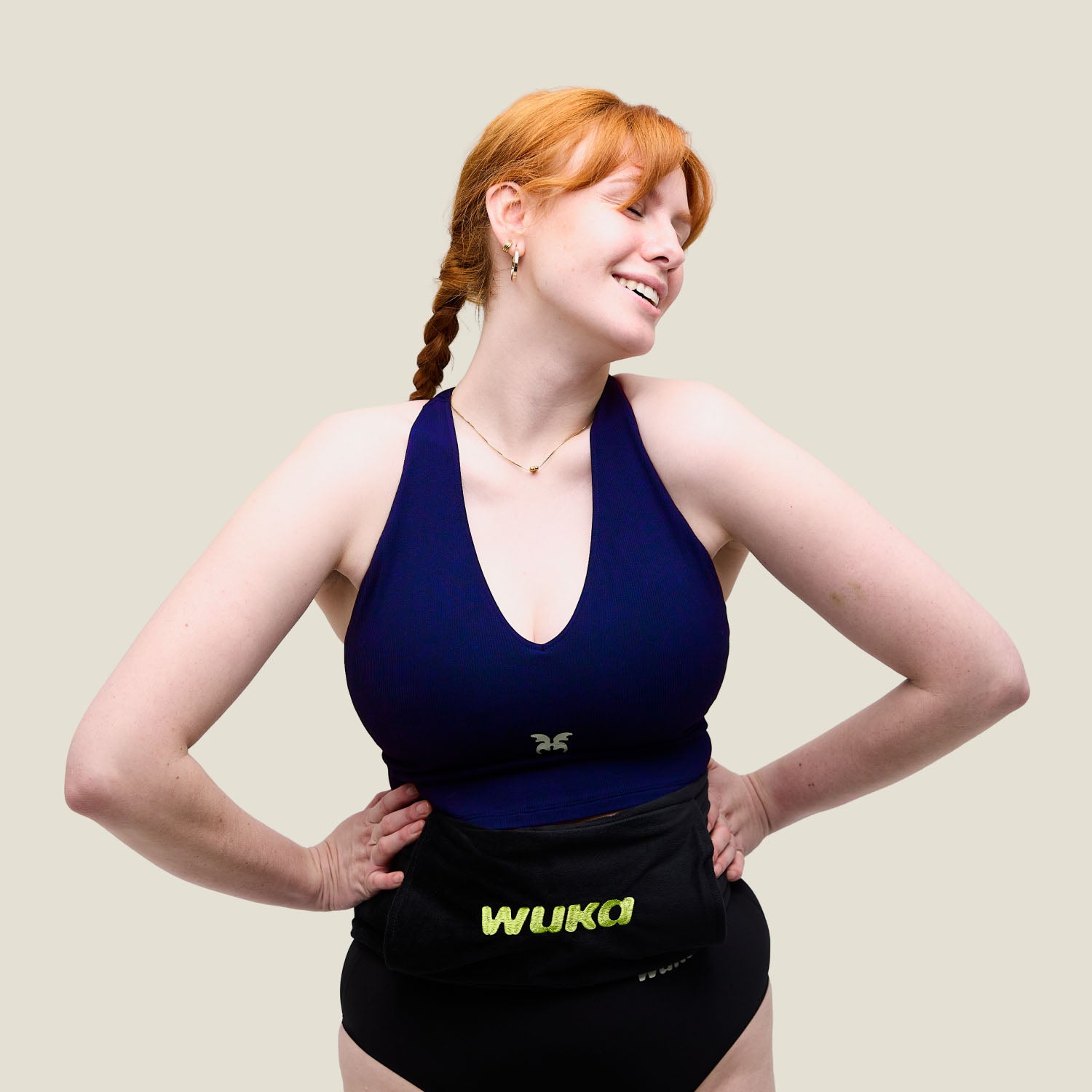 Woman smiling and wearing WUKA hot water bottle around waist for period pain relief