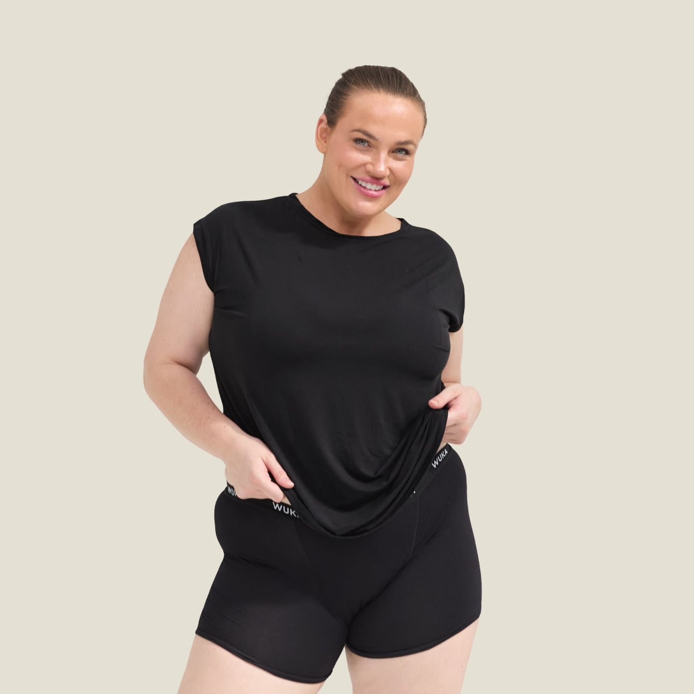 Plus size model wearing WUKA Pyjama Jersey T-Shirt in black, front view with shorts, showcasing menopause sleepwear for cooling comfort.