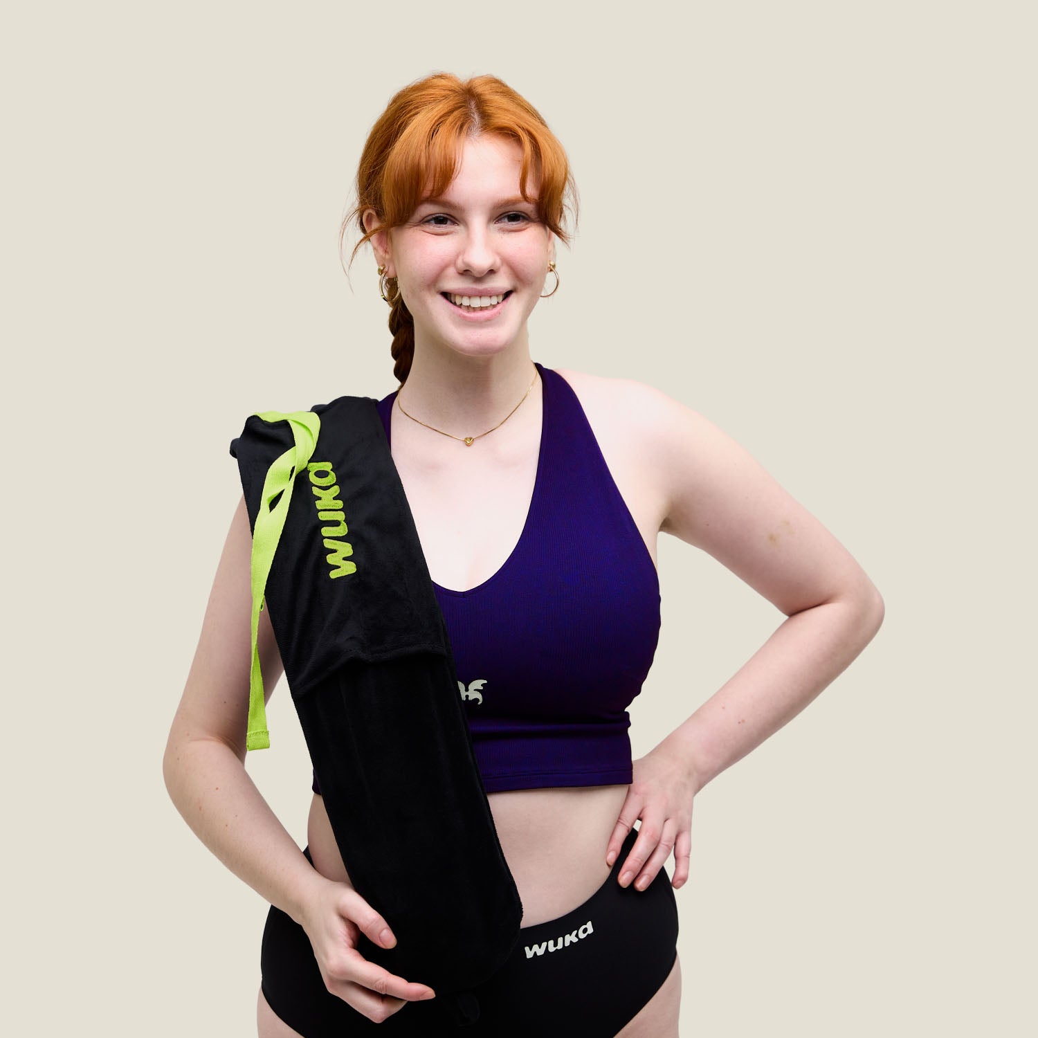 Woman holding WUKA branded extra-long hot water bottle over shoulder in period underwear