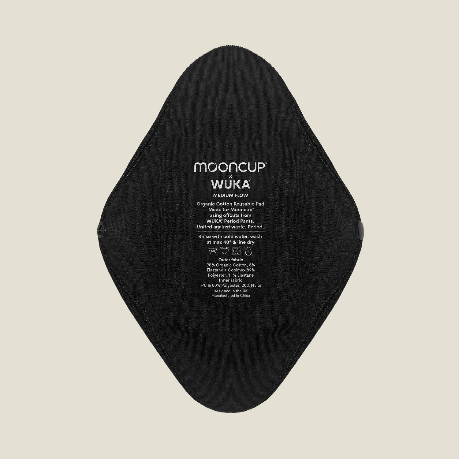 Close-up of WUKA x Mooncup reusable period pad showing organic cotton outer side with printed care instructions for medium flow.