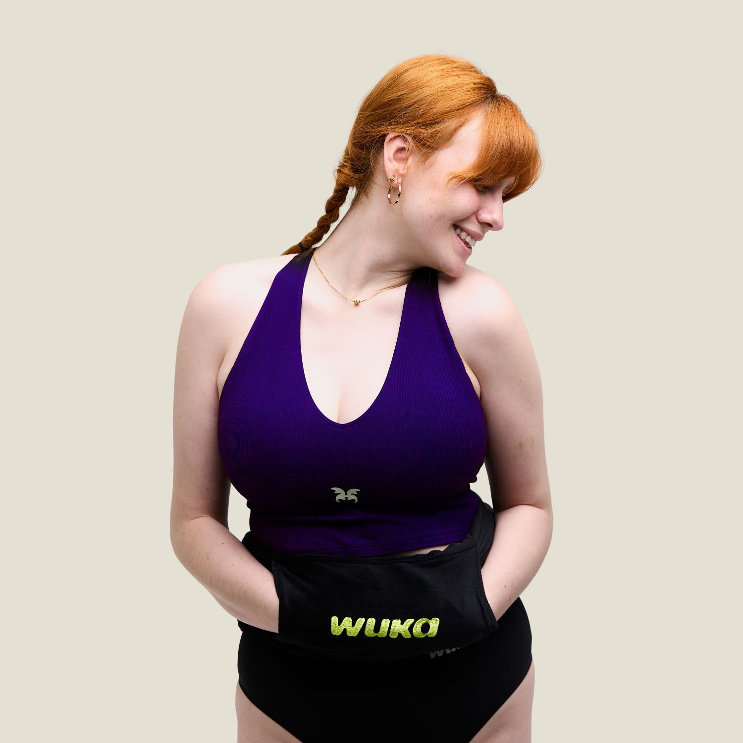 Woman in WUKA period underwear smiling with WUKA hot water bottle tied around waist