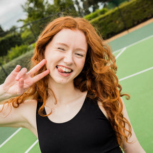 Smiling teen on a sports court wearing WUKA Teen Stretch™ period underwear, reflecting 5-star reviews for playing sport leak-free on periods